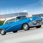 Buyer and salesperson discussing a car deal beside a sedan at a dealership lot.