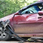 Used-car buyer comparing two sedans and checking insurance cost factors on a smartphone