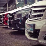 Used car shopper reviewing price sheets with a dealer beside a sedan