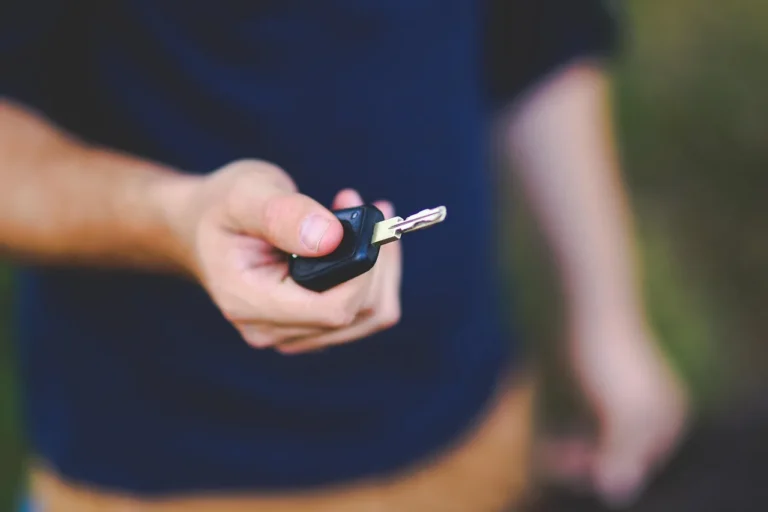 Couple reviewing used car financing papers at a dealership desk with a sedan in the background